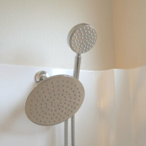 A detachable handheld showerhead is mounted on a white bathroom wall.