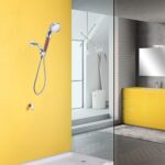 Modern bathroom with yellow walls, fixtures, a wall-mounted handheld showerhead, sink with yellow cabinet and mirror. Glass partition for shower.