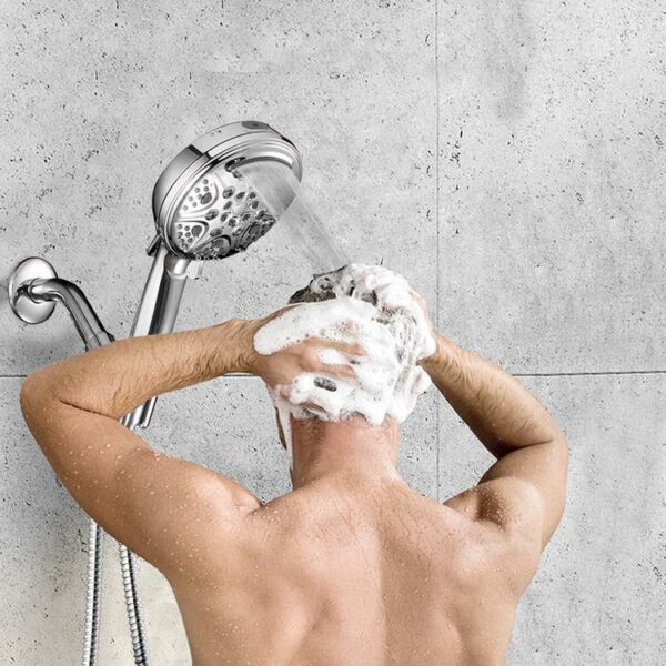 Personne se lavant les cheveux sous une douche courante, faire mousser du savon dans une zone de douche carrelée.