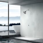 Modern bathroom with large scenic window, gray wall showerhead by white tub, and floor flowing into a water feature.