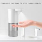 A hand under a touchless soap dispenser with the text "TOUCHLESS, TAKE CARE OF YOUR FAMILY