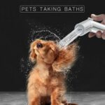 A small dog shakes off water from a showerhead. Caption: "Pets Taking Baths".