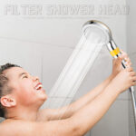 A young boy smiles with eyes closed, holding a showerhead as water flows.