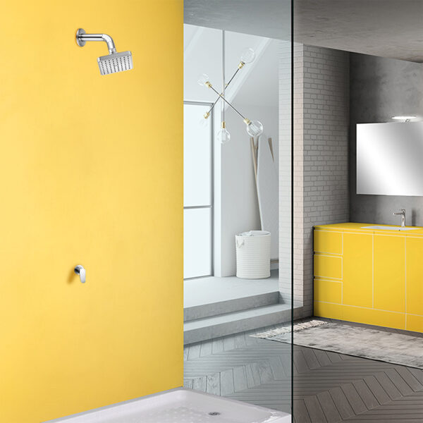 Minimalistic bathroom: bright yellow shower wall, stainless steel showerhead, yellow vanity with mirror, large glass partition, gray tile floor.