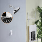 A silver showerhead is mounted above a white control panel. A ladder towel rack holds black and white towels, with green plants in the background.