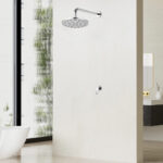 A minimalist shower with a round overhead showerhead and single control knob, next to a modern bathroom with a white bathtub.