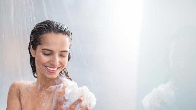 Mujer duchándose con una sonrisa en su cara