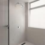 Ducha minimalista con rociador de lluvia redondo de 25cm, control cromado, puerta de cristal y ventana con persianas en pared derecha.