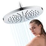 Una mujer se ducha bajo un cabezal de ducha de lluvia redondo de 25 cm montado en la pared, con el agua cayendo a raudales.