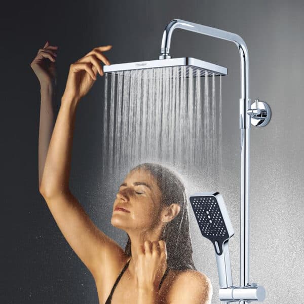 Une femme se tient sous une grande douche à effet pluie chromée, les yeux fermés, le bras levé ; une douche à main est également fixée.