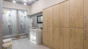 Vestiaire moderne avec casiers en bois, miroir de courtoisie, serviettes, peignoirs et douches doubles à l'arrière.