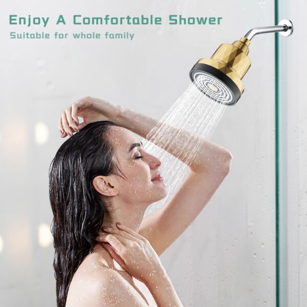 Shower head with gold finish releasing water onto woman enjoying shower experience in bathroom setting.