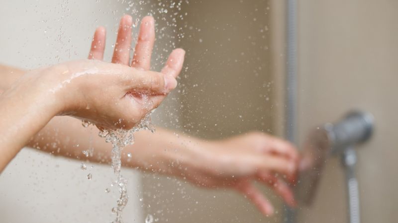 People washing hands under a shower or faucet, emphasizing hygiene and cleanliness essentials.