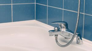 Shower hose with chrome finish and flexible design attached to a modern bathroom faucet.