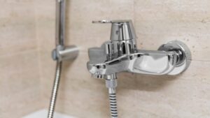 Modern banyo dekoruna ve kolay su kontrolüne uygun, entegre el duşu başlığına sahip şık krom banyo bataryası.