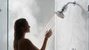 Woman enjoying a shower in a modern bathroom with marble tiles and a rain shower head.