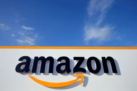 Close-up of Amazon logo on building exterior with blue sky background, showcasing the company's branding and corporate identity.