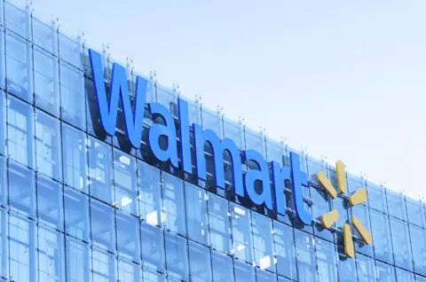 Exterior view of a Walmart store with a glass facade and the Walmart logo prominently displayed.