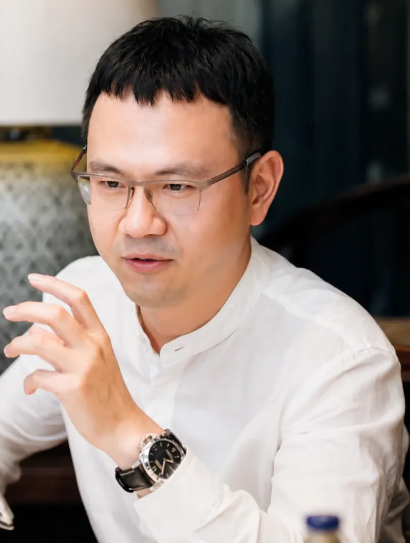 Focused man wearing glasses and a white shirt working on a laptop in an office setting.
