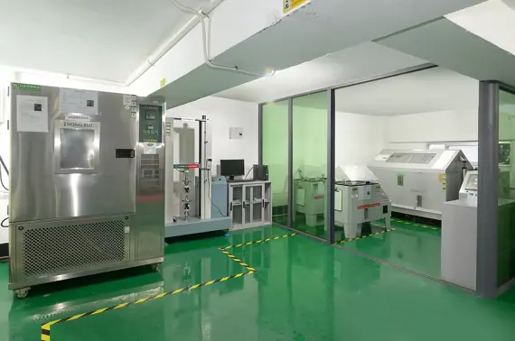 Modern laboratory with stainless steel machines, green flooring, and glass partition walls for scientific research and testing.